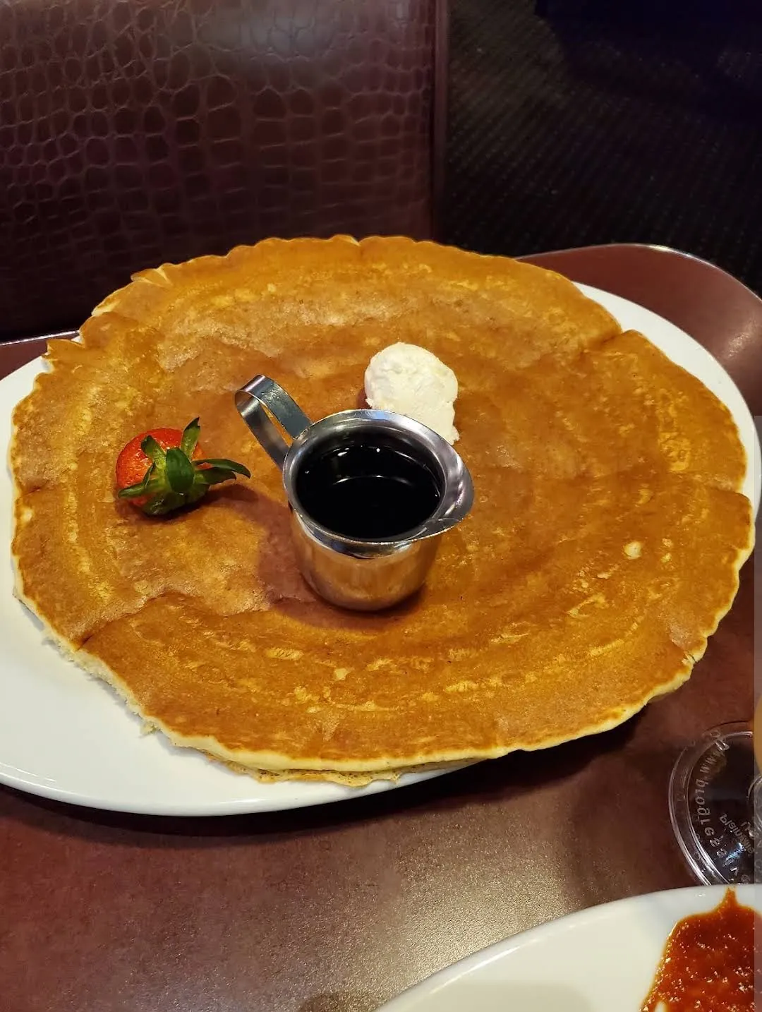 Giant plain pancake with syrup, butter and a strawberry at Hash House A Go Go